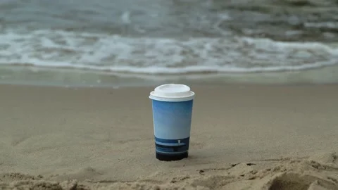 A cup of coffee or tea stands on the sand, on the seashore, ocean. waves over a  Stock Footage 208945853