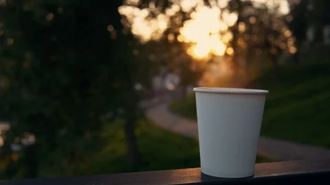 A cup of coffee or tea with steam over the urban landscape at sunset. Stock Footage 95444427