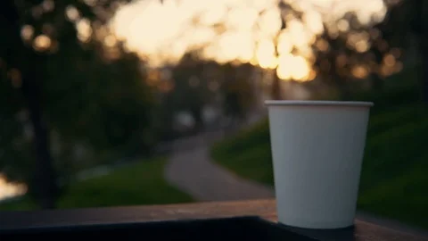 A cup of coffee or tea with steam over the urban landscape at sunset. Stock Footage 96155795