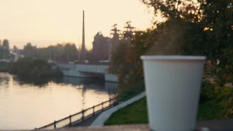 A cup of coffee or tea with steam over the urban landscape at sunset. Stock Footage 96155874