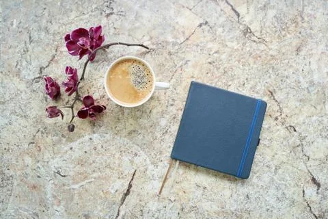 Cup of coffee, orchid, notepad flat lay on marble table Stock Photos