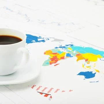 Cup of coffee over world map and financial documents - studio shot 写真素材