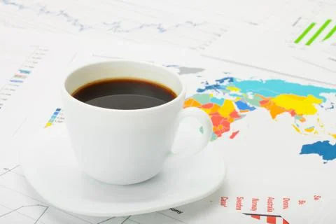 Cup of coffee over world map and financial documents 写真素材