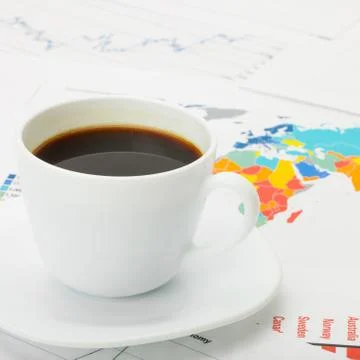 Cup of coffee over world map and financial documents 写真素材