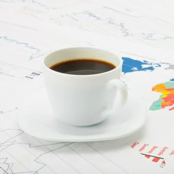 Cup of coffee over world map and financial documents - studio shot Stock Photos
