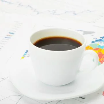 Cup of coffee over world map and financial documents Stock Photos