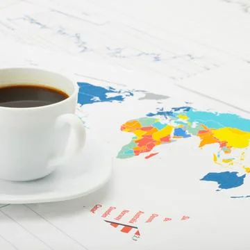 Cup of coffee over world map and financial documents - studio shot Coffee ... Stock Photos