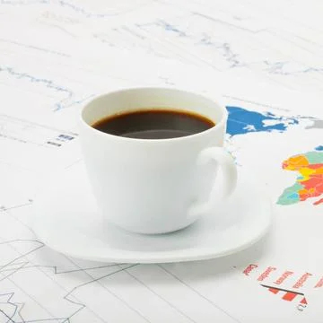 Cup of coffee over world map and financial documents - studio shot Coffee ... Stock Photos