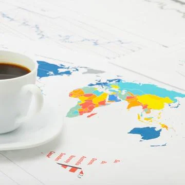 Cup of coffee over world map and financial documents - studio shot Coffee ... Stockfoto's