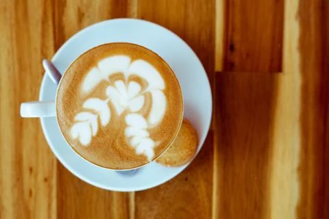 A cup of coffee with pattern in a white cup with cookie on wooden background Foto stock
