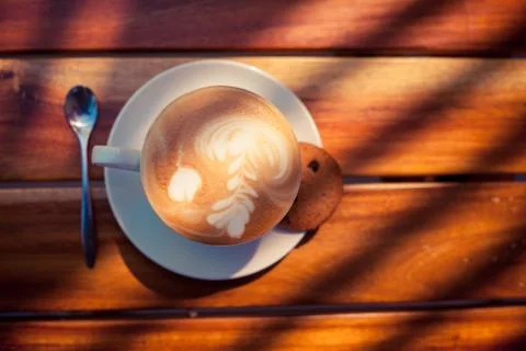 A cup of coffee with pattern in a white cup with cookie on wooden background 写真素材