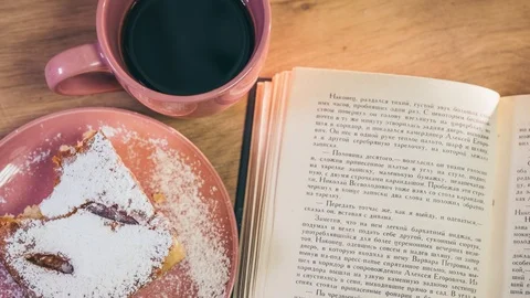 A cup of coffee, a pie and paging pages of the book - using the Stop Motion Video stock 123632861