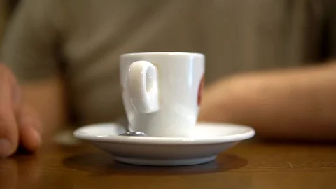 A Cup of coffee is on a plate on the table, close-up, the man picks it up Stock Footage 92086123