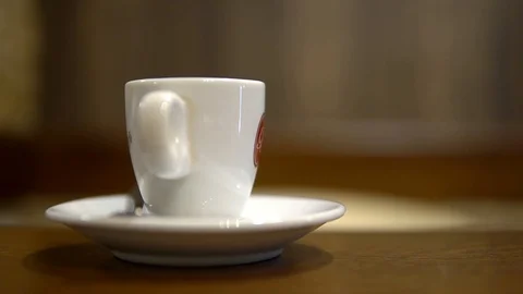 A Cup of coffee is on a plate on the table, close-up, a person comes, sits down Stock Footage 92161613