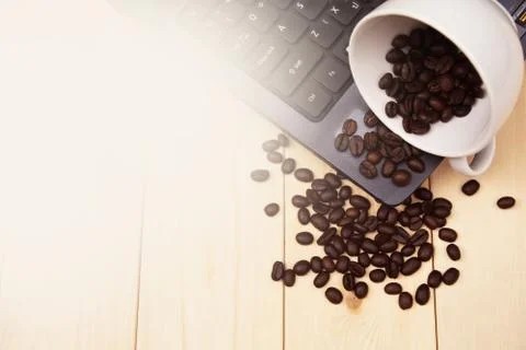 A cup of coffee put on table on laptop and spread coffee beans Foto stock