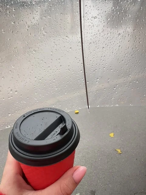 A cup of coffee in a red cup against the background of rain Stock Footage 258145033