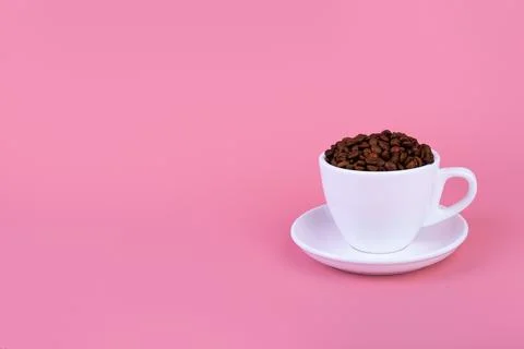 Cup of coffee with roasted beans on isolated pink background. Side view with  Stock Photos