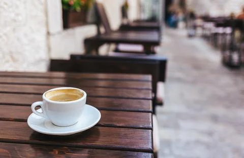 Cup of coffee on a rustic wooden table in a street cafe. Place for text. Stock Photos