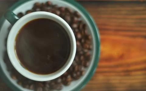 A cup of coffee on a saucer with fried coffee beans Foto stock