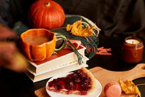 Cup of coffee in shape of pumpkin, cherry pie, macaroons, candle among fall Stock Photos