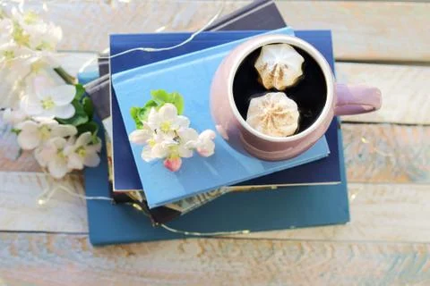 Cup of coffee, a stack of books, apple flowers on a wooden windowsill Stock Photos