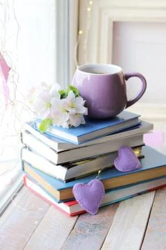Cup of coffee, a stack of books decorated with hearts, apple flowers Stock Photos