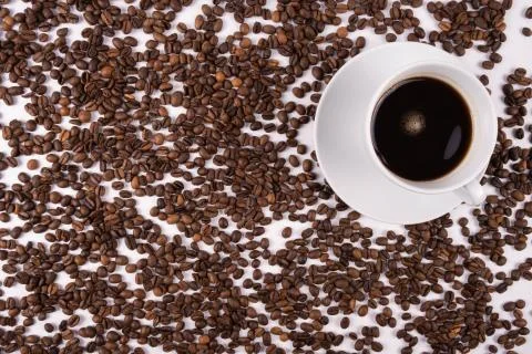 Cup with coffee stands on a table, scattered coffee grains Stock Photos