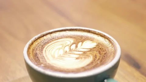 Cup of coffee stands on a wooden table in a coffee shop, closeup video. 動画素材 334648745