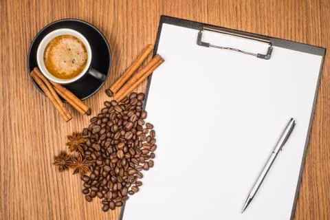 A cup of coffee, star anise, cinnamon and a clipboard with blank paper for yo Stock Photos