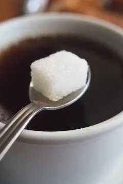 Cup of coffee with sugar cube on spoon Stock Photos