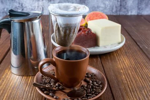 Cup of coffee surrounded by beans, cloth filter and guava sweet and curd chee Stock Photos