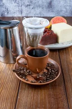 Cup of coffee surrounded by beans, cloth filter and guava sweet and curd chee Stock Photos
