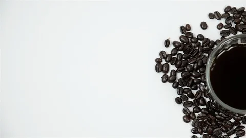 A cup of coffee surrounded by coffee beans on white background. Stock Footage 100789994