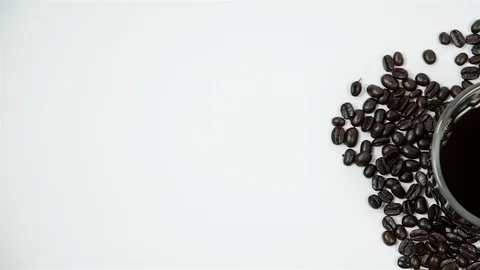 A cup of coffee surrounded by coffee beans on white background. Stock Footage 100790477