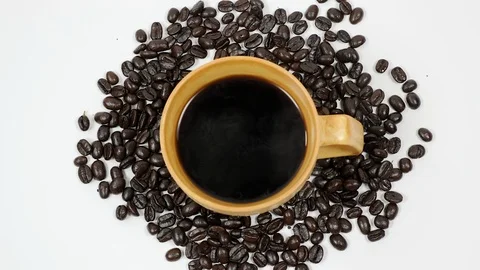 A cup of coffee surrounded by coffee beans on white background. Stock Footage 100792161