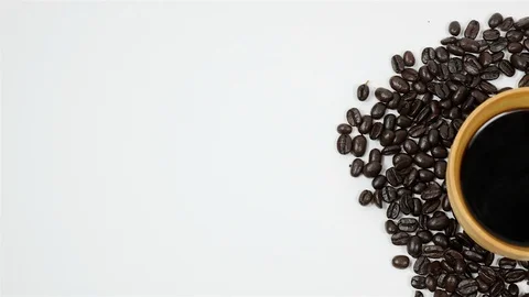 A cup of coffee surrounded by coffee beans on white background. Stock Footage 100793547