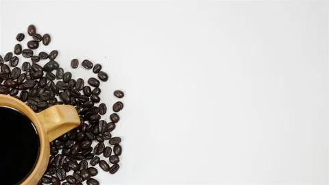 A cup of coffee surrounded by coffee beans on white background. Stock Footage 100794207