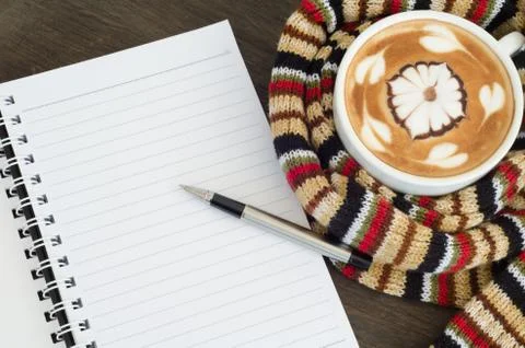 Cup of coffee surrounded the warm scarf  and note book Stock Photos