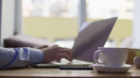 Cup of coffee on table against employed man typing on laptop Stock Footage 205500009
