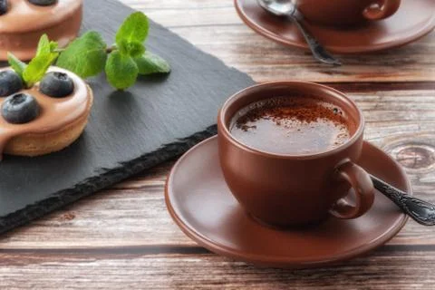 Cup of coffee on the table and a fruit basket on a serving board, fruit muffi Stock Photos