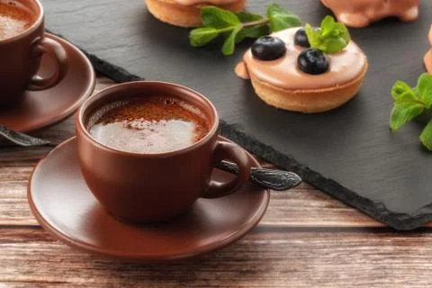 Cup of coffee on the table and a fruit basket on a serving board, fruit muffi Stock Photos