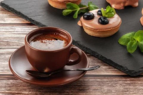 Cup of coffee on the table and a fruit basket on a serving board, fruit muffi Stock Photos