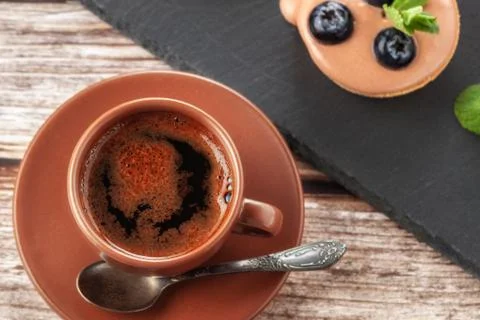 Cup of coffee on the table and a fruit basket on a serving board, fruit muffi Stock Photos