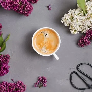Cup of coffee on the table with beautiful lilac flowers. Stock Photos