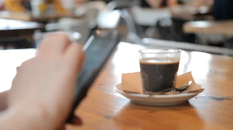 Cup of coffee on the table in cafes and the hands of man with phone 스톡 동영상 63498319