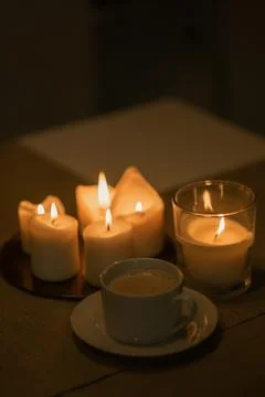 A cup of coffee is on the table next to the candles. c Stock Photos
