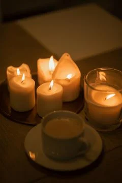 A cup of coffee is on the table next to the candles. c Stock Photos