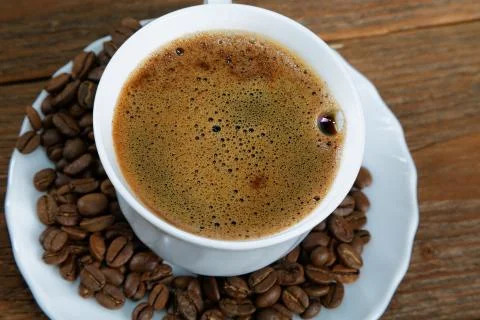 Cup with coffee on the table next to coffee beans Stock Photos