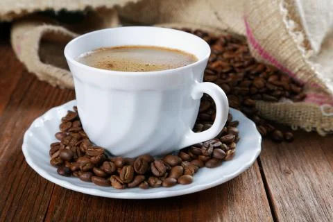 Cup with coffee on the table next to coffee beans Stock Photos