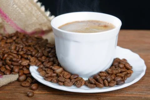 Cup with coffee on the table next to coffee beans Stock Photos